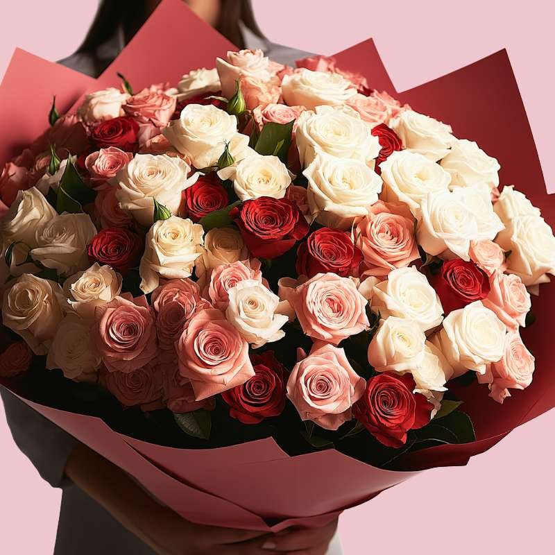 Bouquet of red, white, and pink roses held against a pink background