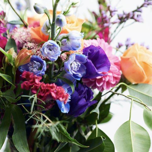 Close of this vibrant flower arrangement with blue delphinium and purple lisianthus