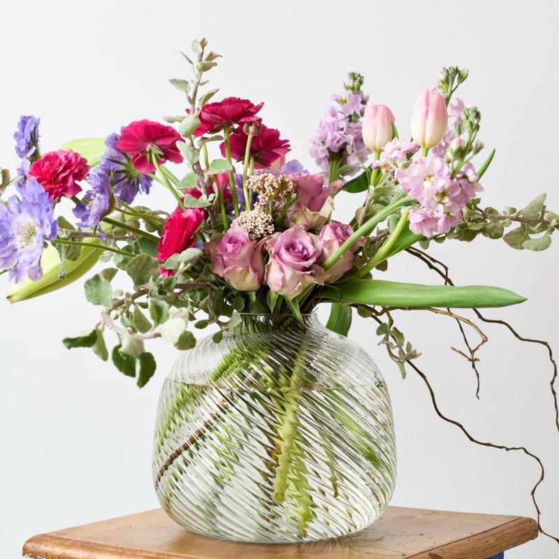 Playful Elegance vase arrangement includes: Pink or Cerise Ranunculus (seasonal and may be replaced) Lilac Scabiosa Lilac or light pink roses Pink stocks (seasonal and may be replaced) Light pink tulips ((seasonal and may be replaced) St Joseph Lilies delivered for birthday gift from Fabulous Flowers