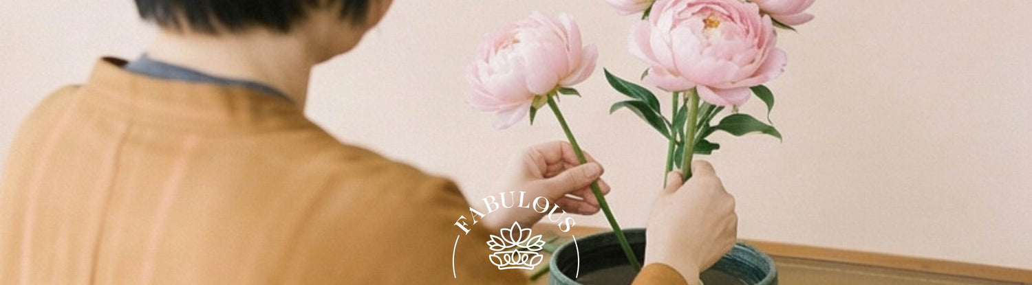 Person carefully arranging pink peonies in a ceramic vase using Japanese ikebana flower arrangement techniques — Fabulous Flowers & Gifts