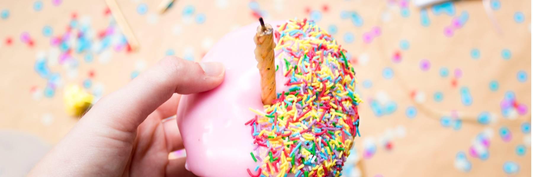 The Art and Importance of Sending Nice Birthday Messages a donut and sprinkles with candle - Fabulous Flowers