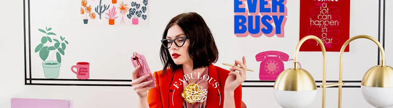 Woman dressed in a bold red suit at a stylish desk, surrounded by motivational wall art including 'For Ever Busy' - Top 10 Boss's Day Gift Ideas.