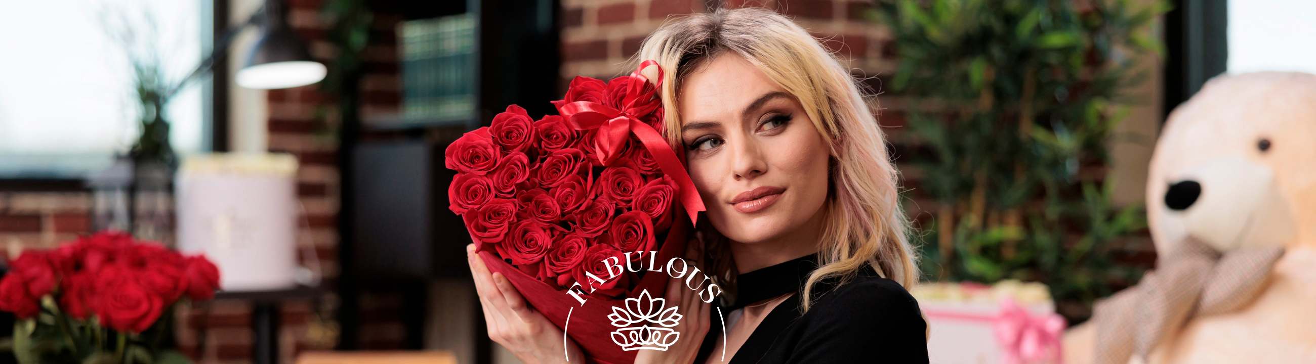 Blonde woman in black holds heart-shaped red rose arrangement with ribbon in cosy loft setting, Fabulous branding.
