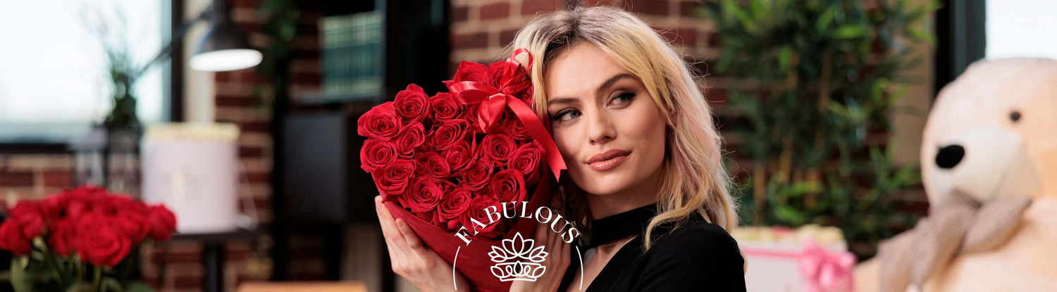 Blonde woman in black holds heart-shaped red rose arrangement with ribbon in cosy loft setting, Fabulous branding.