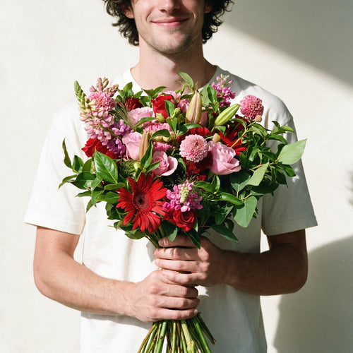Medium Romantic Splendour bouquet of red and pink roses, gerberas and lilies held by a smiling man in a white t-shirt, Fabulous Flowers South Africa