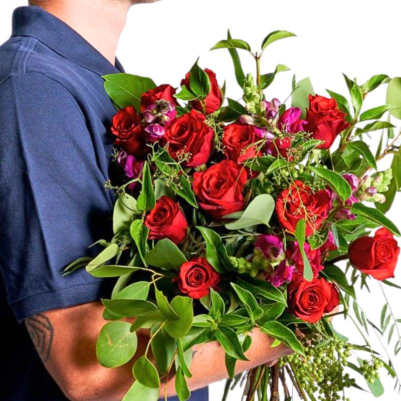 Close-up of A Magical Love Story Bouquet showing red roses, fresh foliage and textured greens