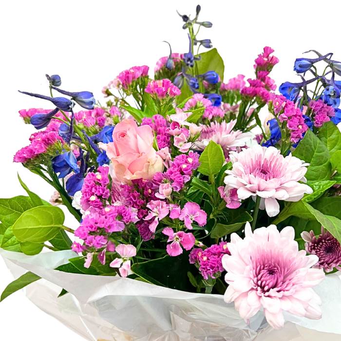Close-up of Alchemy Posy showing pink blossoms, lilac flowers and bright blue accents with fresh greenery