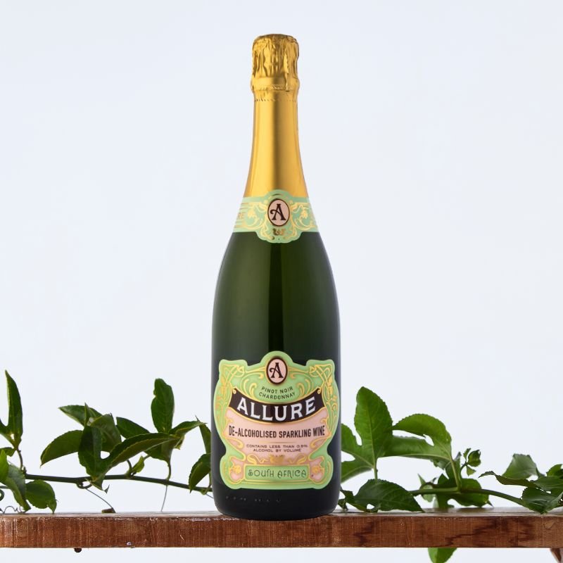 Allure Low-Alcoholic Sparkling Wine 750 ml bottle with gold foil top on wooden shelf, styled with green foliage