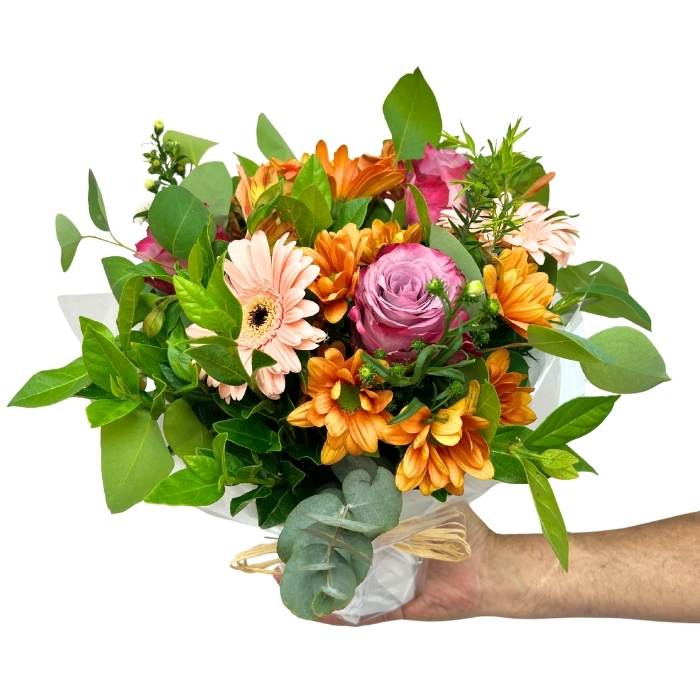 Posy of flowers held by a hand on a white background