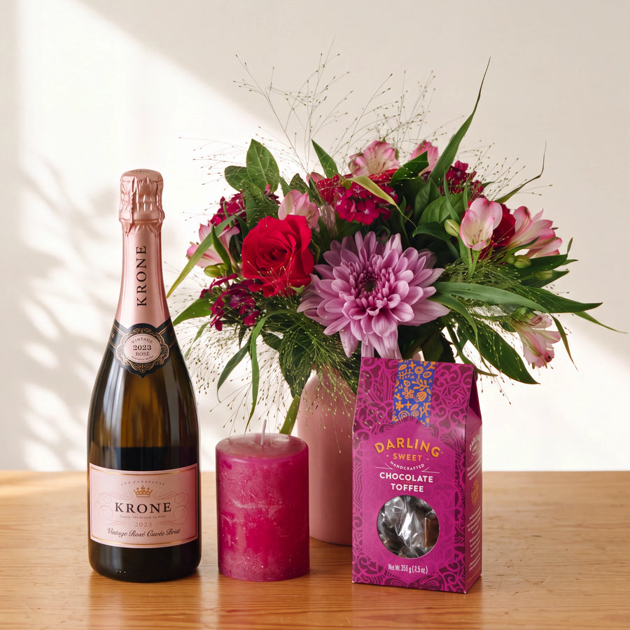 Bloom and Bubble flowers and champagne gift set from Fabulous Flowers, red roses and pink blooms in a blush jar with Krone Rosé Cuvée Brut, a berry-pink candle and Darling Sweet chocolate toffee