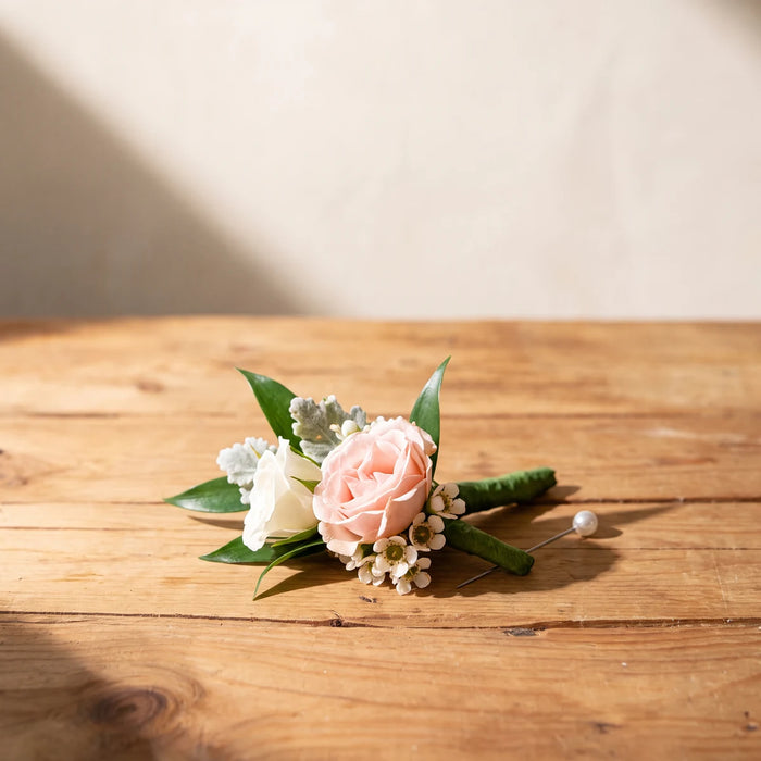 Blush pink rose, white rose and waxflower boutonniere on a pine table, Fabulous Flowers South Africa
