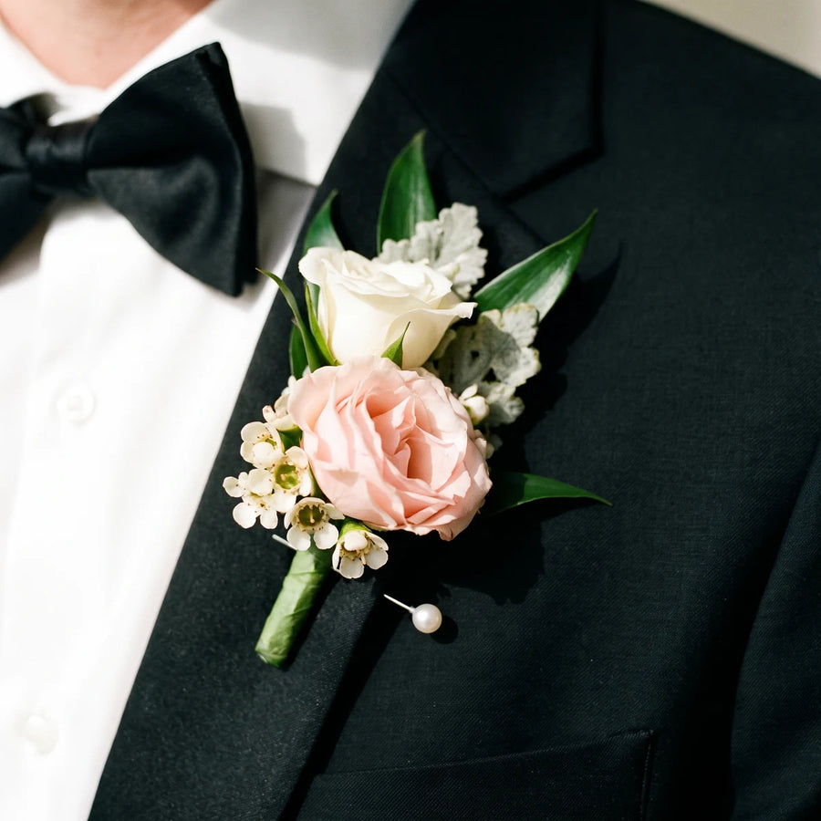 Close-up of a blush pink rose and white waxflower buttonhole on a tuxedo lapel, Fabulous Flowers South Africa