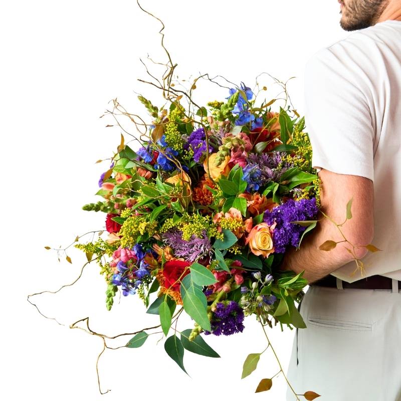 Person holding a large, colorful bouquet of flowers against a white background