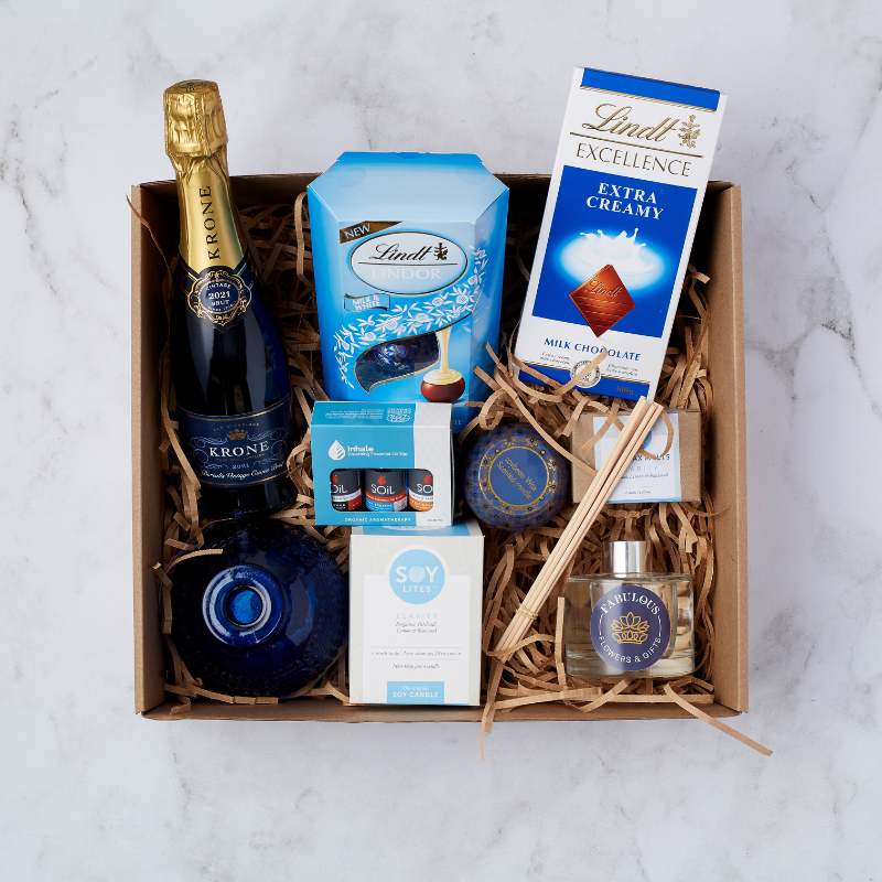 Bubbles & Bliss Treat Box with a bottle of Krone champagne, Lindt chocolates, essential oils, soy candle, and luxury bath products, arranged in a gift box with natural fillers.