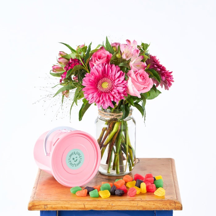 Candy Crush - Flower Guy showcases a pink flower arrangement in a jar with a pastel bucket tipped over and colourful sweets scattered.