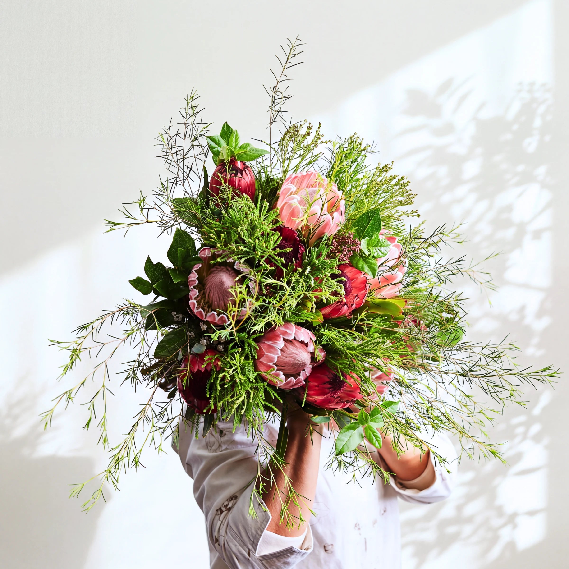 Cape Town Protea Bouquet of pink and red proteas with wild fynbos greenery, held in the sunlight