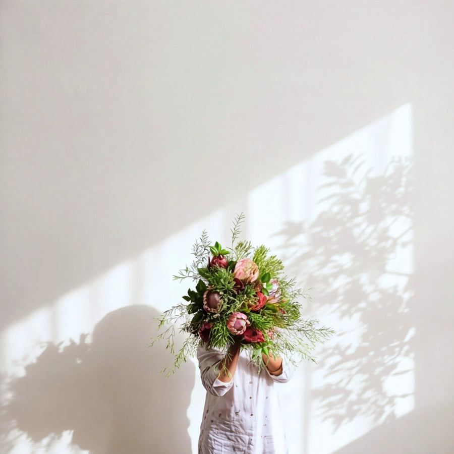 The Cape Town Protea Bouquet of proteas and fynbos, held up in soft sunlight