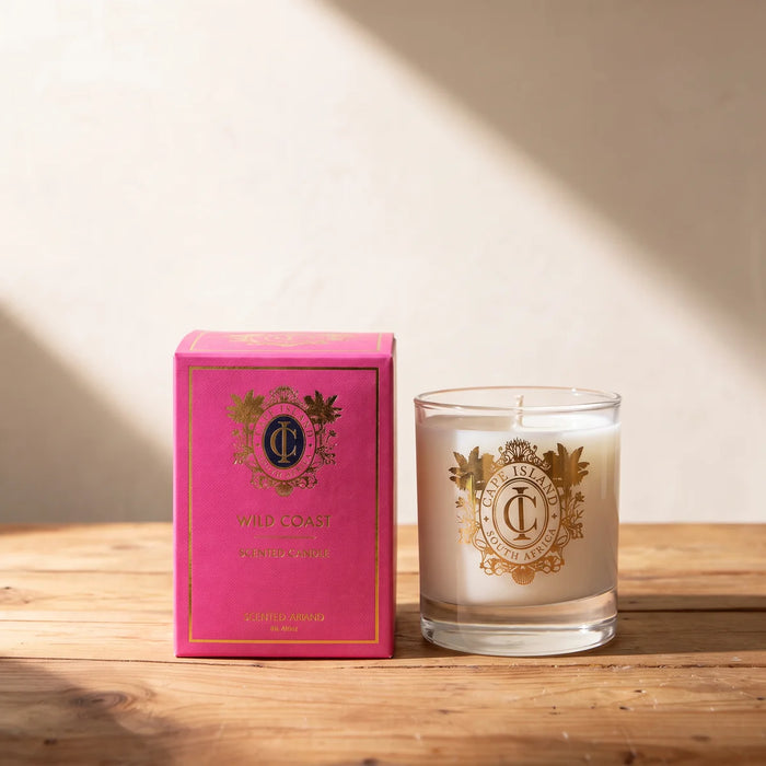 Pink gift box beside a white soy candle in a glass tumbler with a gold crest on a pine table, Fabulous Flowers South Africa