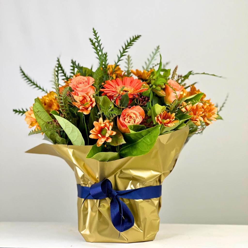 Celebrate Flower Arrangement with mixed orange flowers wrapped in gold paper and a blue ribbon - Fabulous Flowers
