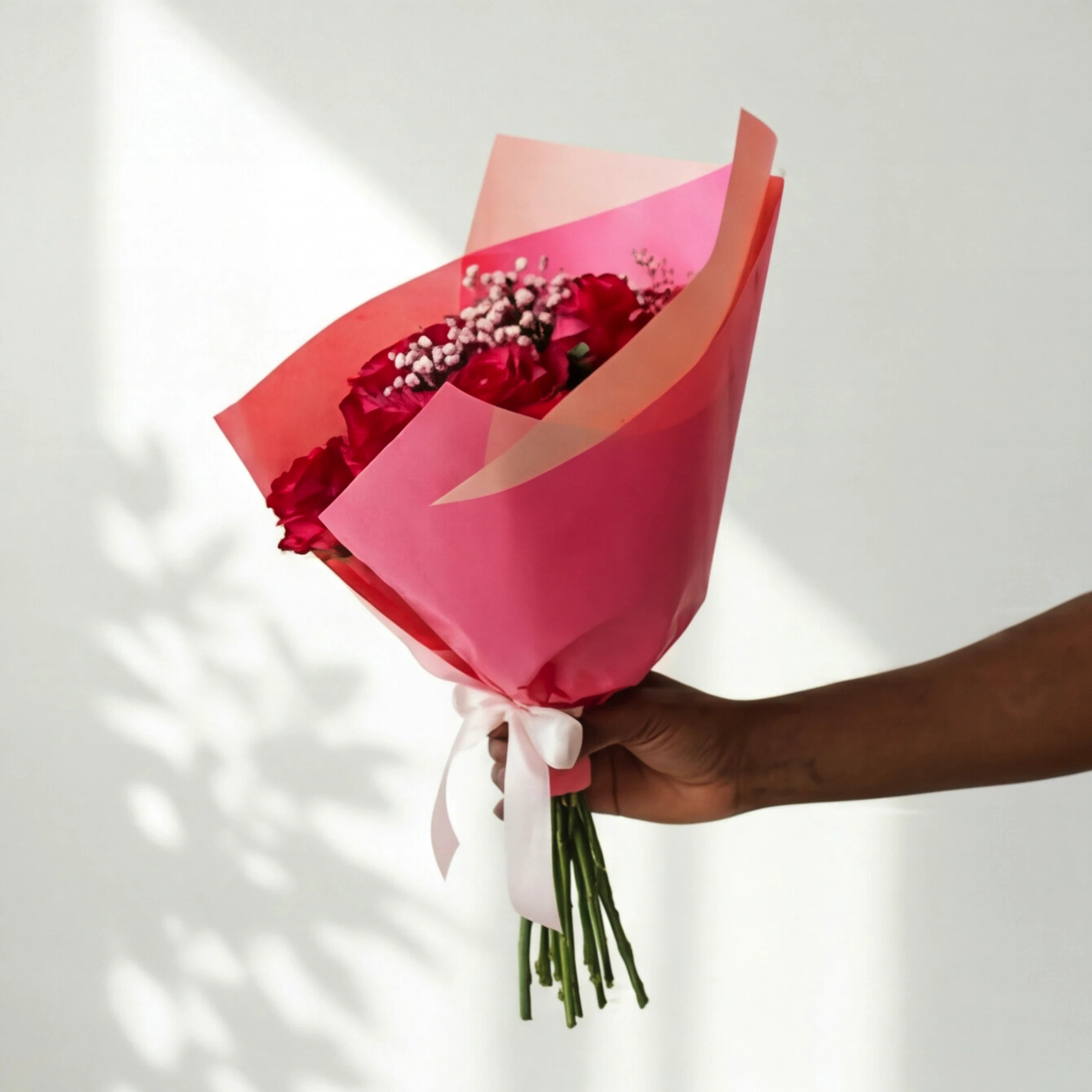 The Cerise Crush red rose bouquet wrapped in cerise and pink paper with a pink satin bow
