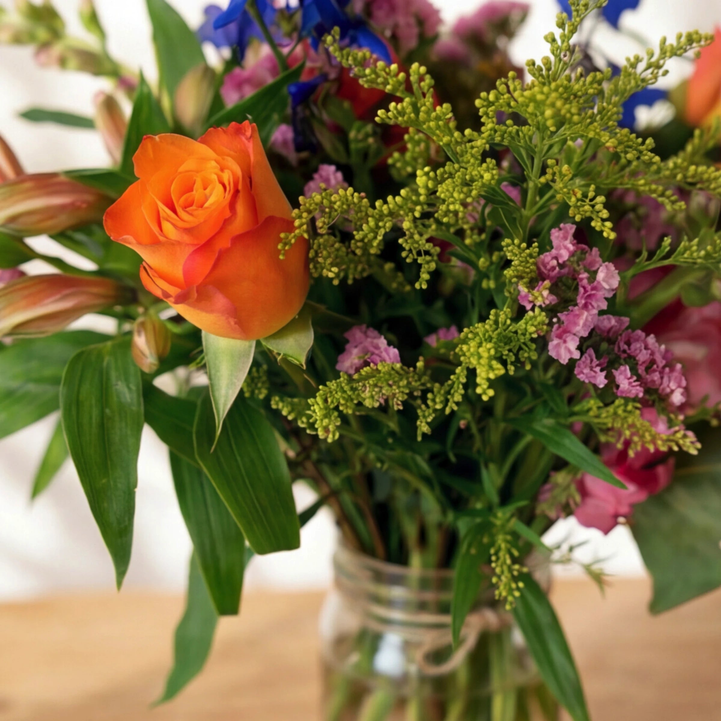 Close-up of an orange rose with lime solidago and pink limonium in Cheer in a Jar by Fabulous Flowers Cape Town