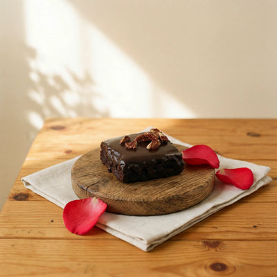 Chocolate Brownie with dark ganache glaze and pecans on oak board with red rose petals by Fabulous Flowers Cape Town