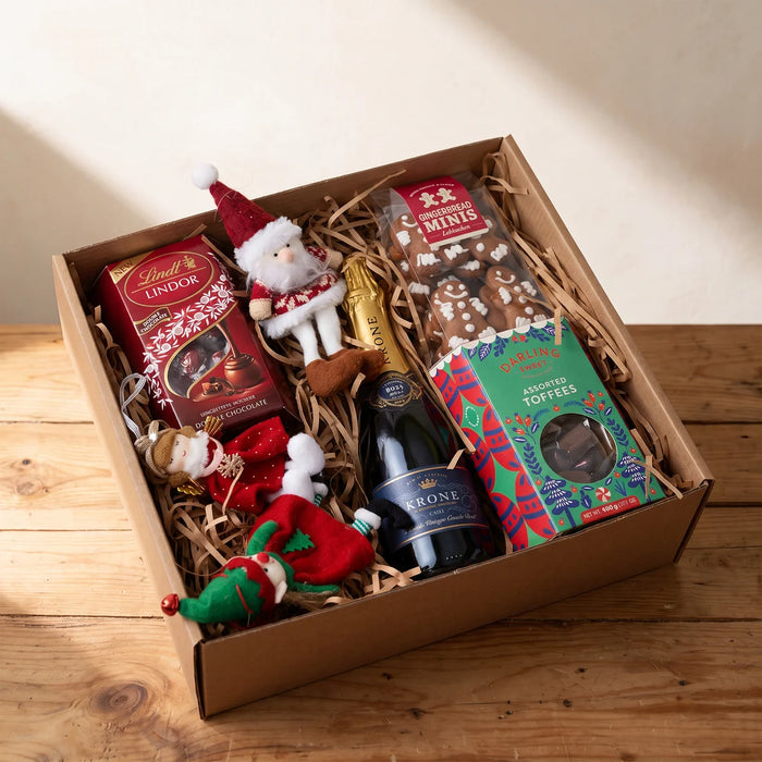 Open kraft gift box with sparkling wine, Lindt chocolates, gingerbread, toffees and three plush Christmas ornaments, Fabulous Flowers South Africa