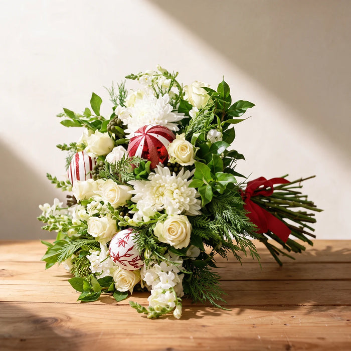 Christmas bouquet of white roses, white chrysanthemums and red and white baubles tied with a red ribbon on a pine table, Fabulous Flowers South Africa