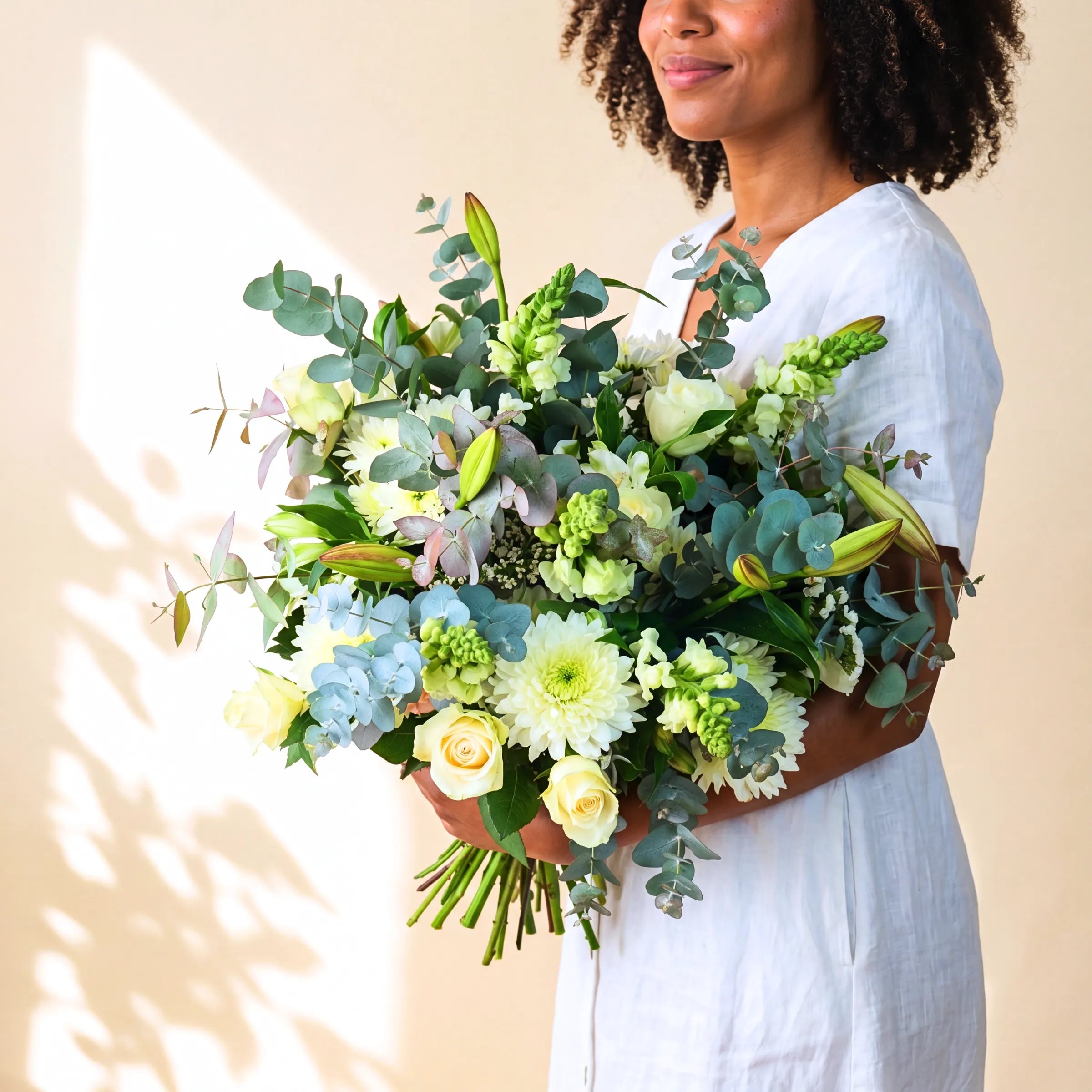 Classic White Bouquet hand-tied with cream roses, white chrysanthemums, blue hydrangea, green snapdragons and silver eucalyptus by Fabulous Flowers