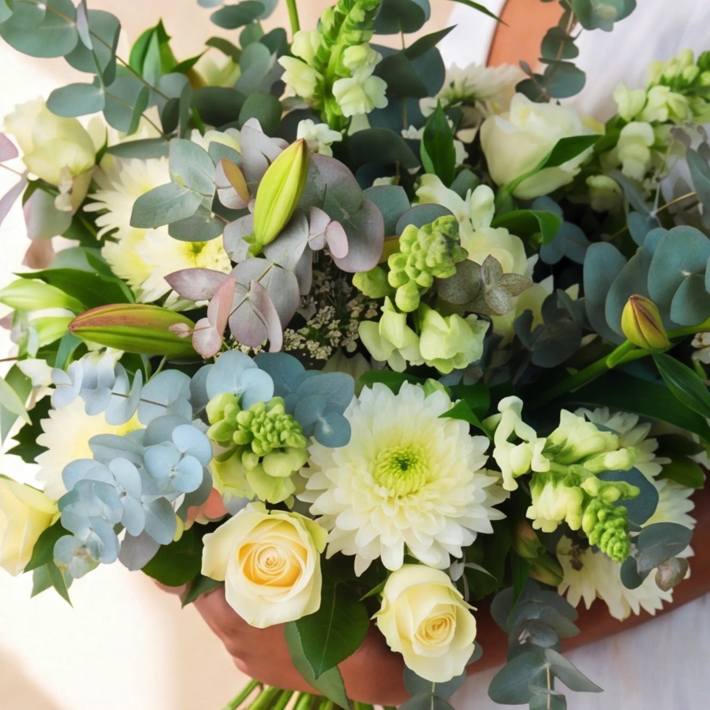 Top view of the Classic White Bouquet with cream roses, white chrysanthemums, blue hydrangea, green bells of Ireland and silver dollar eucalyptus