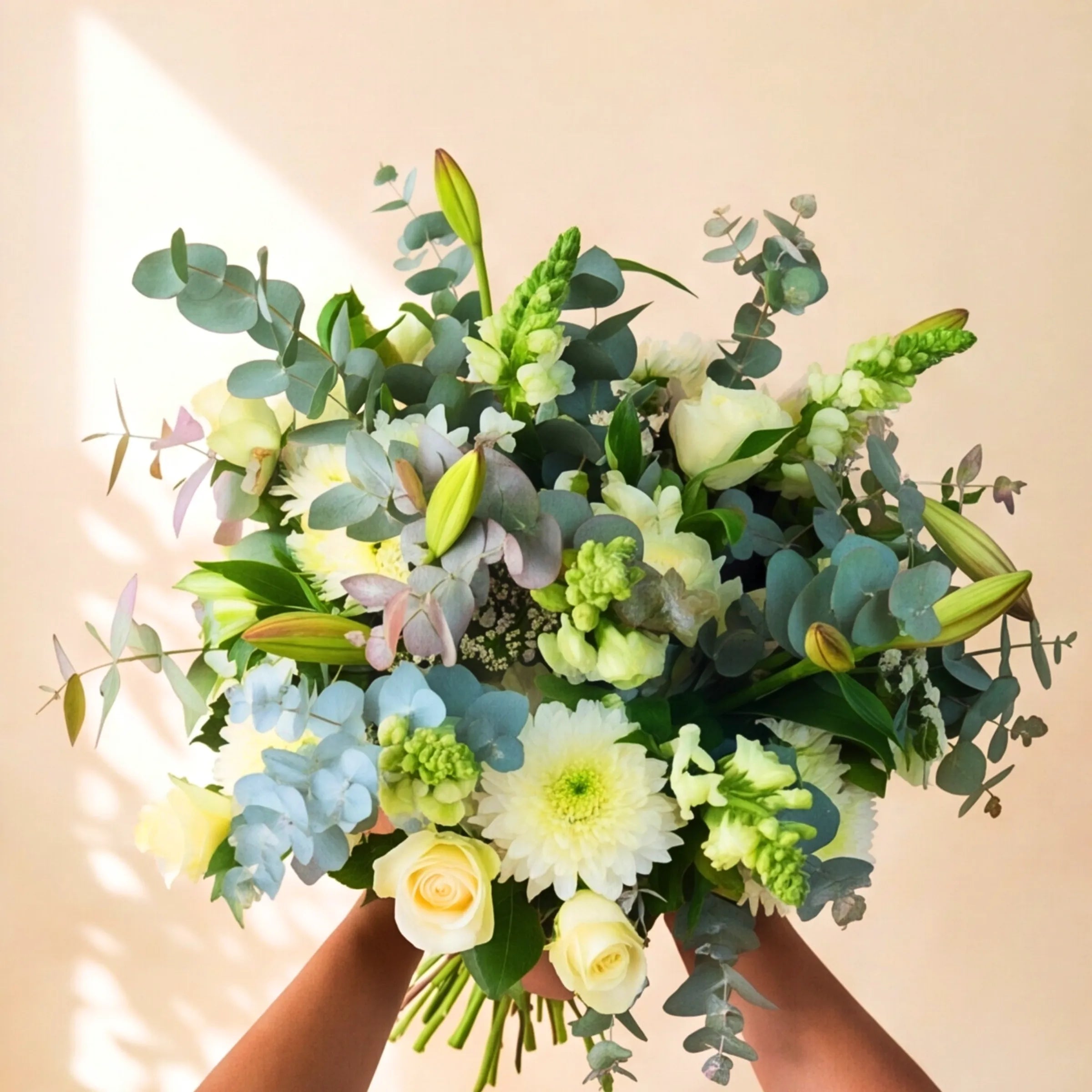 Classic White Bouquet abundant ivory, white and pale blue hand-tied bouquet held in the light, Fabulous Flowers Claremont studio