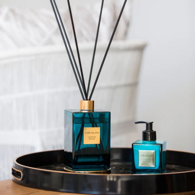 Two blue diffusers with black reeds on a black tray against a white background