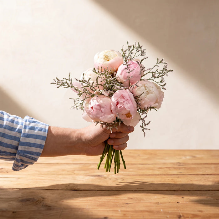 Hand holding out the Clouds of Love peony posy with sea lavender