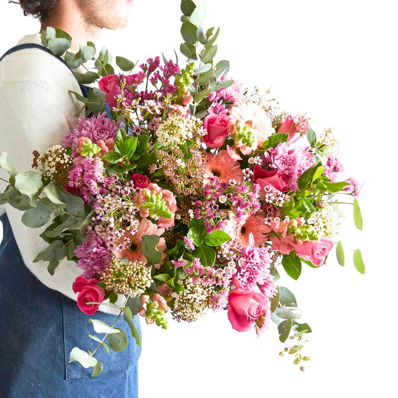 Person holding a large bouquet of pink and green flowers against a white background