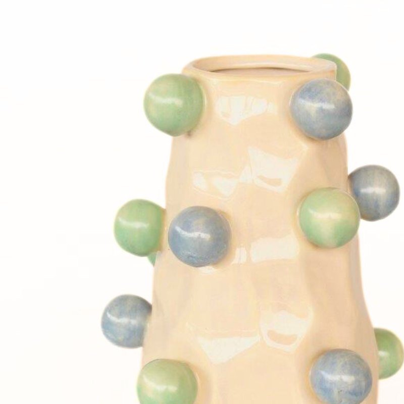 Cylindrical ceramic vase with green and blue spherical protrusions on a white background