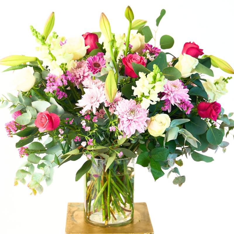Large pastel lower arrangement in a glass vase on a white background