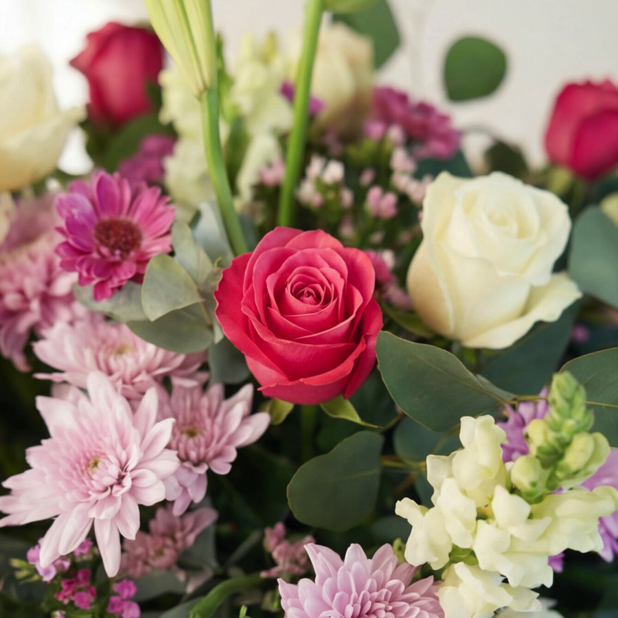 Close-up of a cerise rose with a white rose, pink gerbera and lilac chrysanthemums in the arrangement.