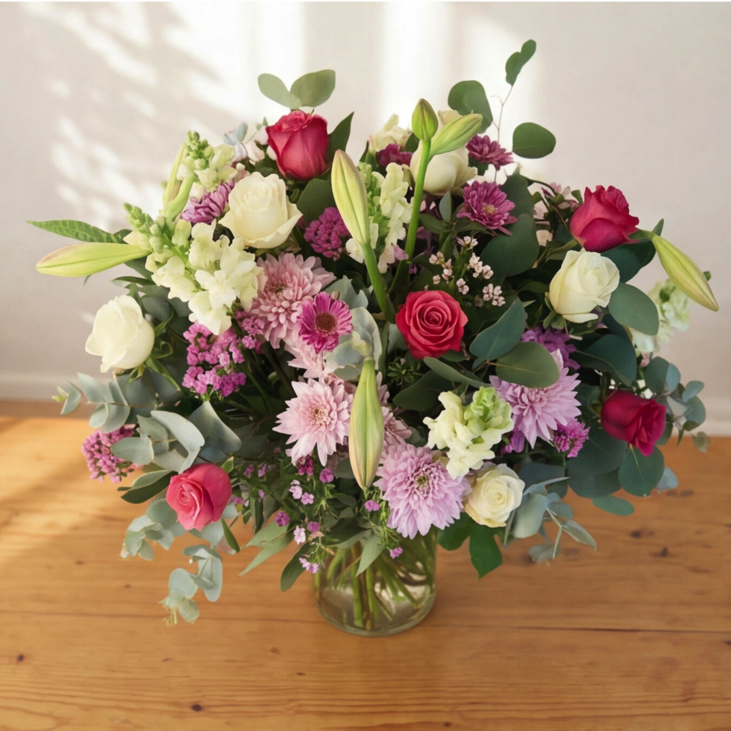 Creative Elegance arrangement in a glass vase, pink and white roses, lilac chrysanthemums, gerberas and lily buds.