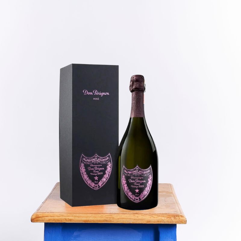 Dom Pérignon Rosé Vintage 2009 champagne bottle with elegant pink label and matching black gift box displayed on a wooden table.