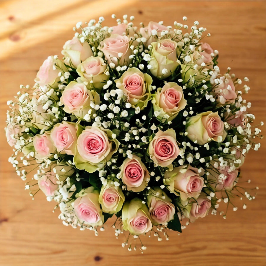 Top down view of blush pink roses and white gypsophila arranged in the Duchess flower box