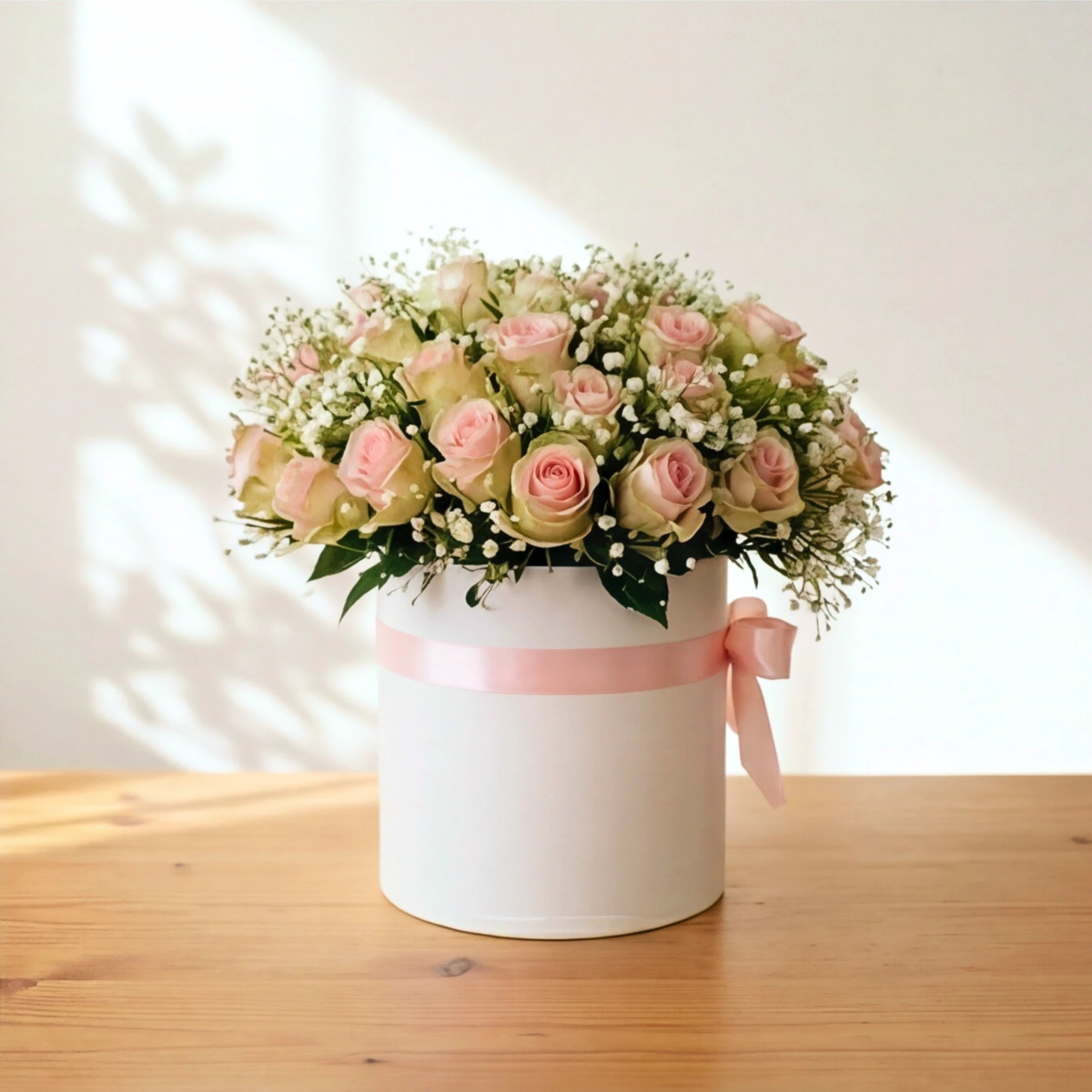Duchess white hatbox arrangement of pink roses and baby's breath on a wooden table