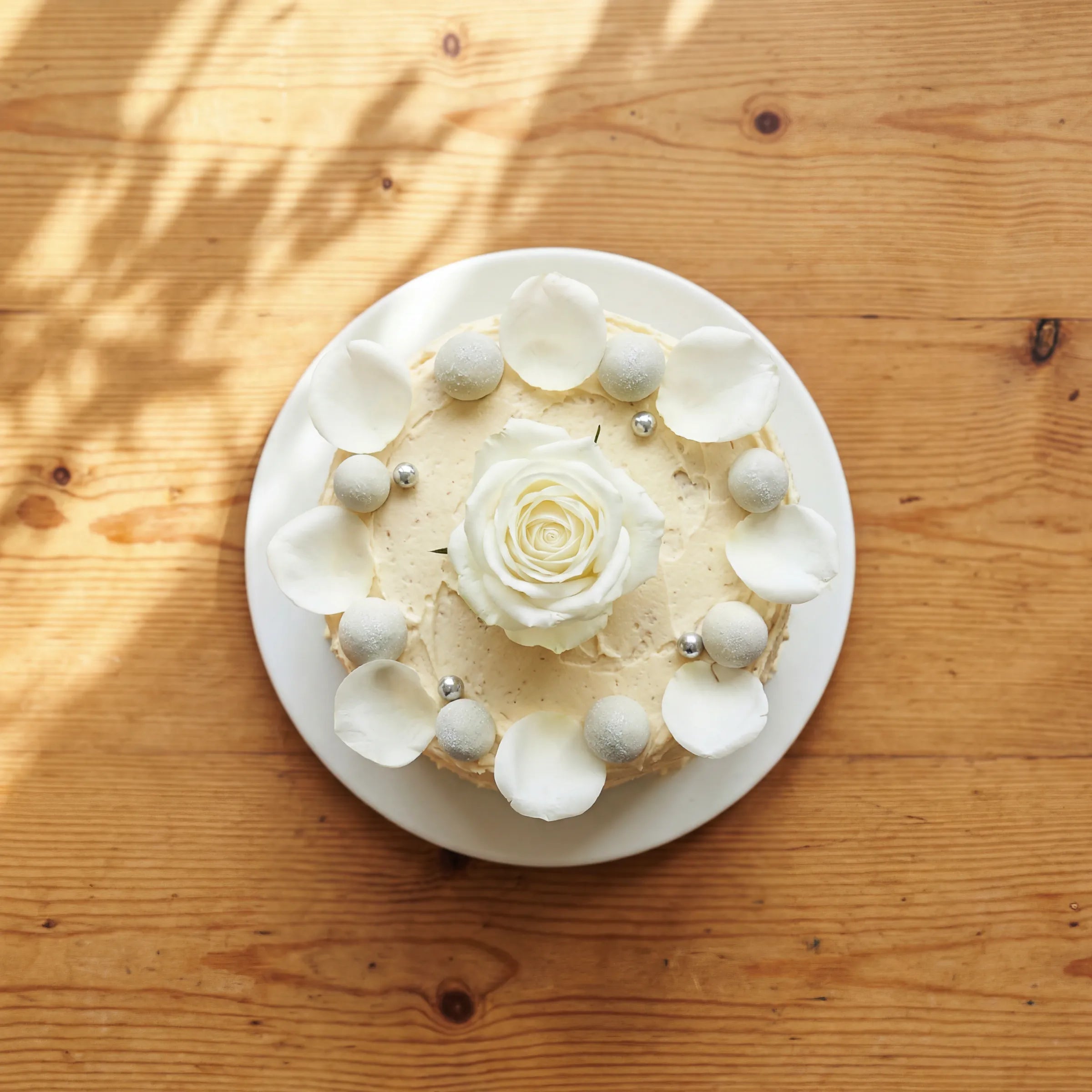 Top-down Elegant Rose Celebration Cake with petal crown and pearl border, hand-decorated in Claremont