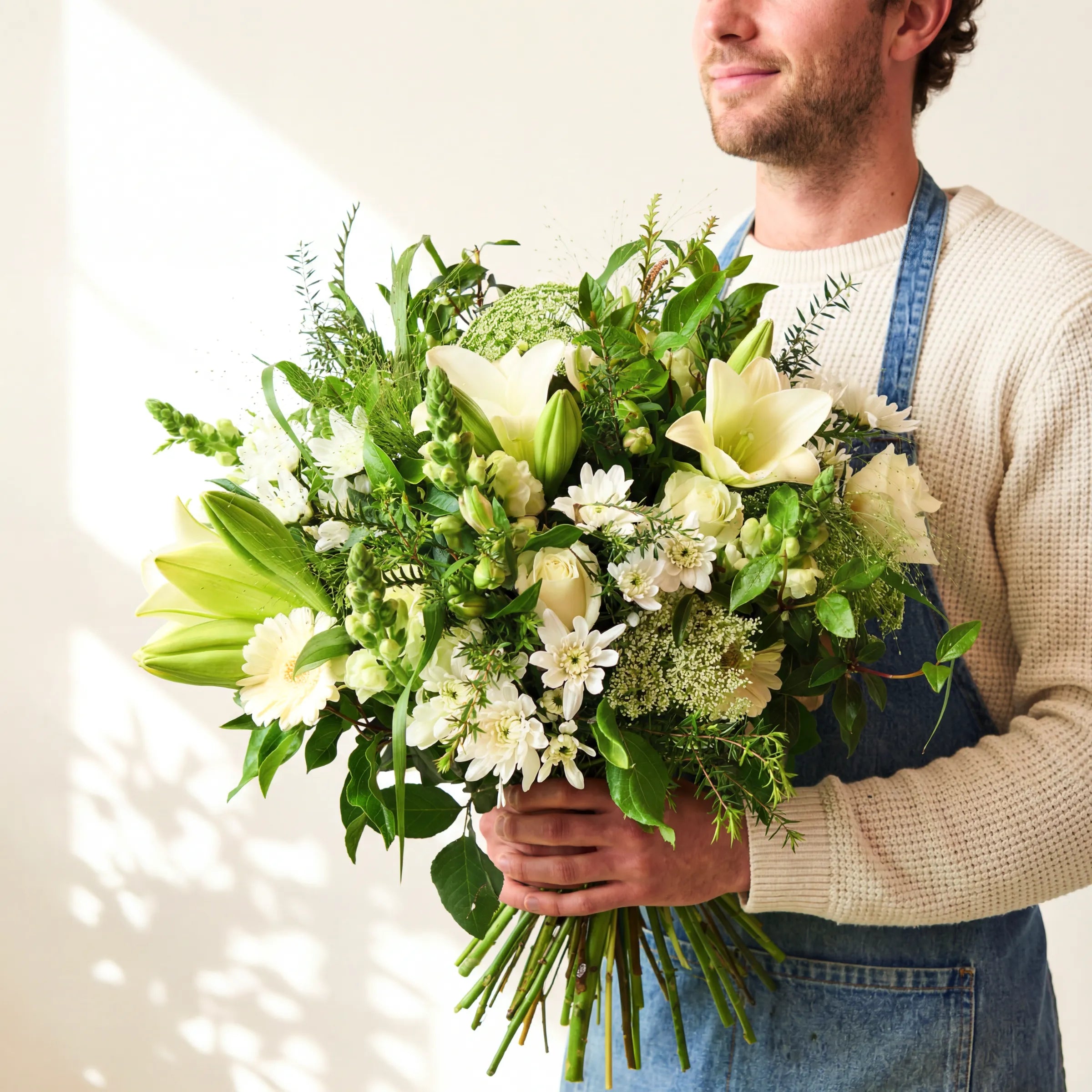 Elegant White Bouquet, a garden-style hand-tie of white lilies, roses and chrysanthemums, held by a Fabulous Flowers florist