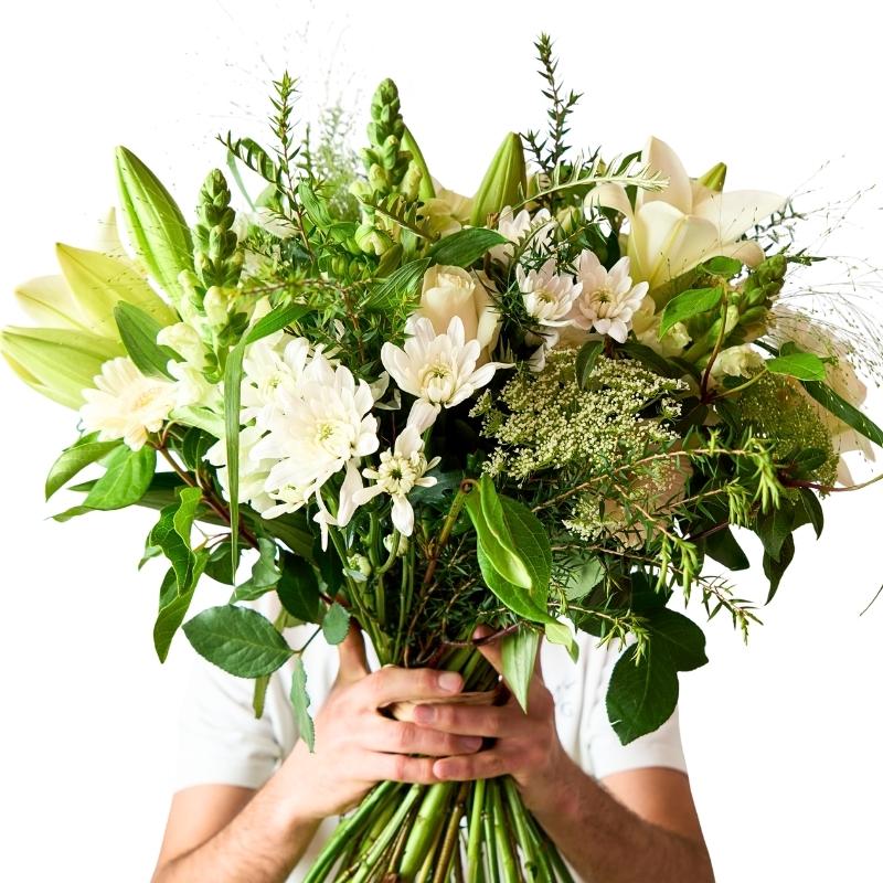 Elegant white bouquet close-up with ivory lilies, white roses and airy greenery