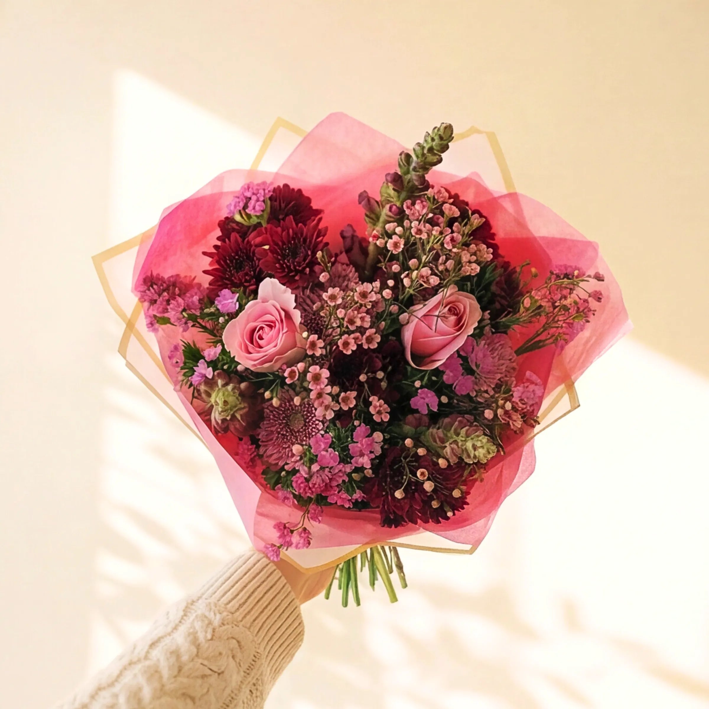 Pink roses bouquet in pink wrap held to the light, with chrysanthemums and waxflower, same-day Cape Town and Joburg delivery