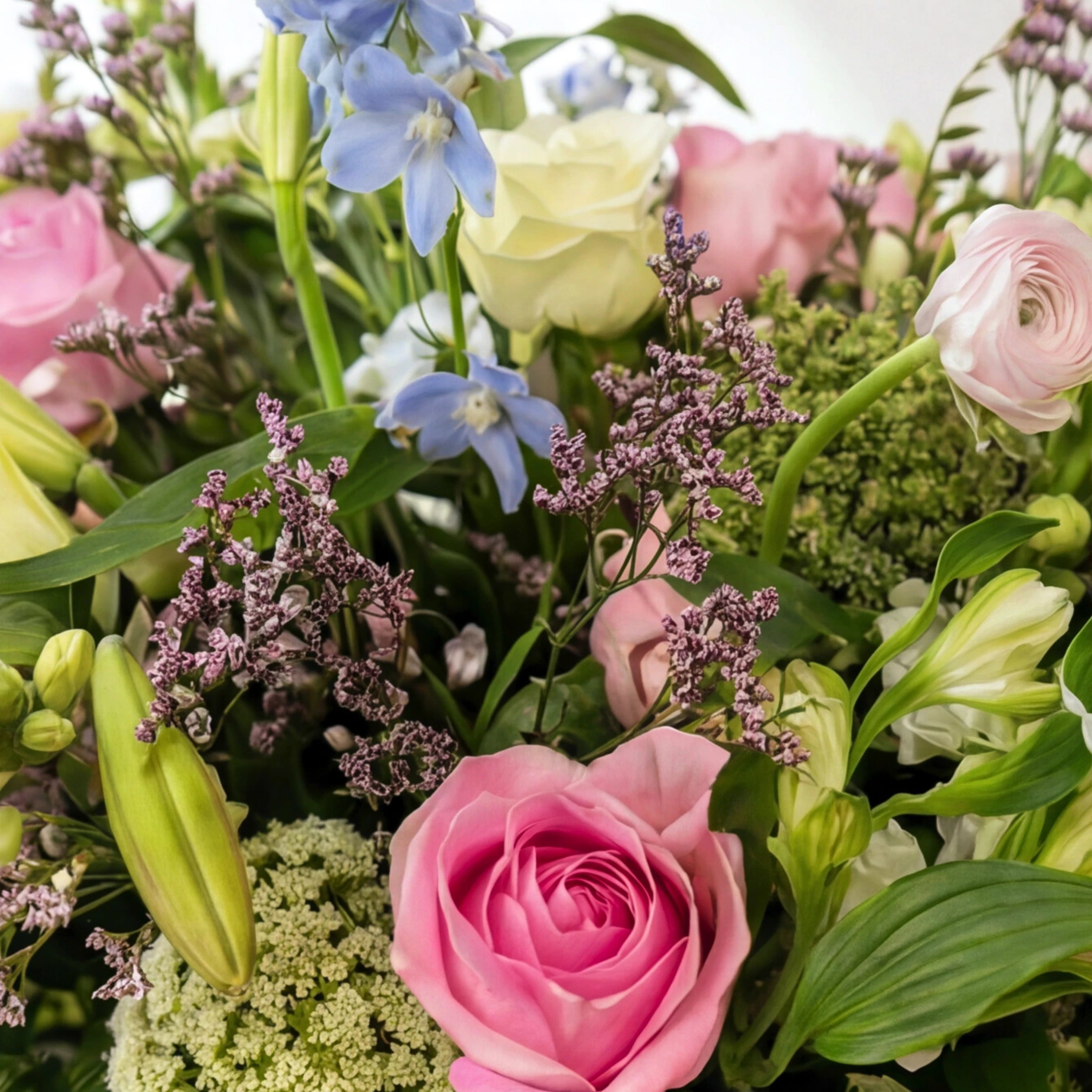 Detail of pastel flowers in English Garden arrangement with pink rose, blue delphinium, ranunculus and Queen Anne's lace