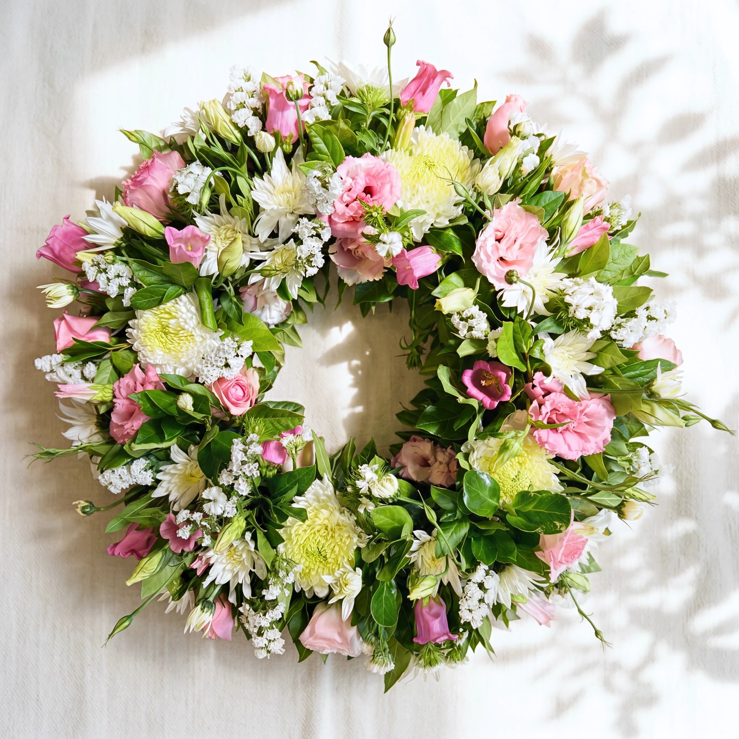 Eternal Spring funeral wreath flowers in soft pink and white with lisianthus, chrysanthemums and greenery