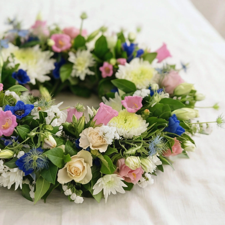 Side view of the Forget Me Not memorial wreath showing cream roses, blue delphinium and love-in-a-mist