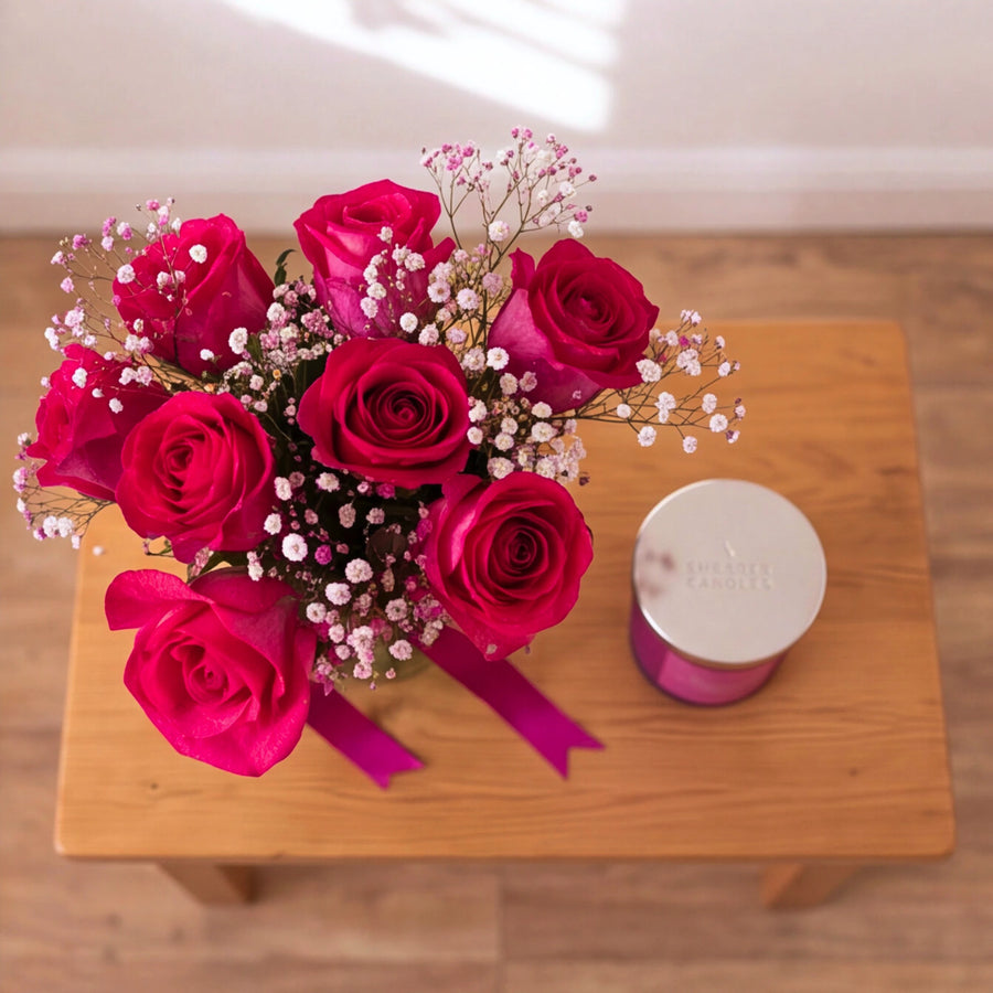Hot pink rose arrangement in a glass vase with Shearer Tropical Watermelon candle