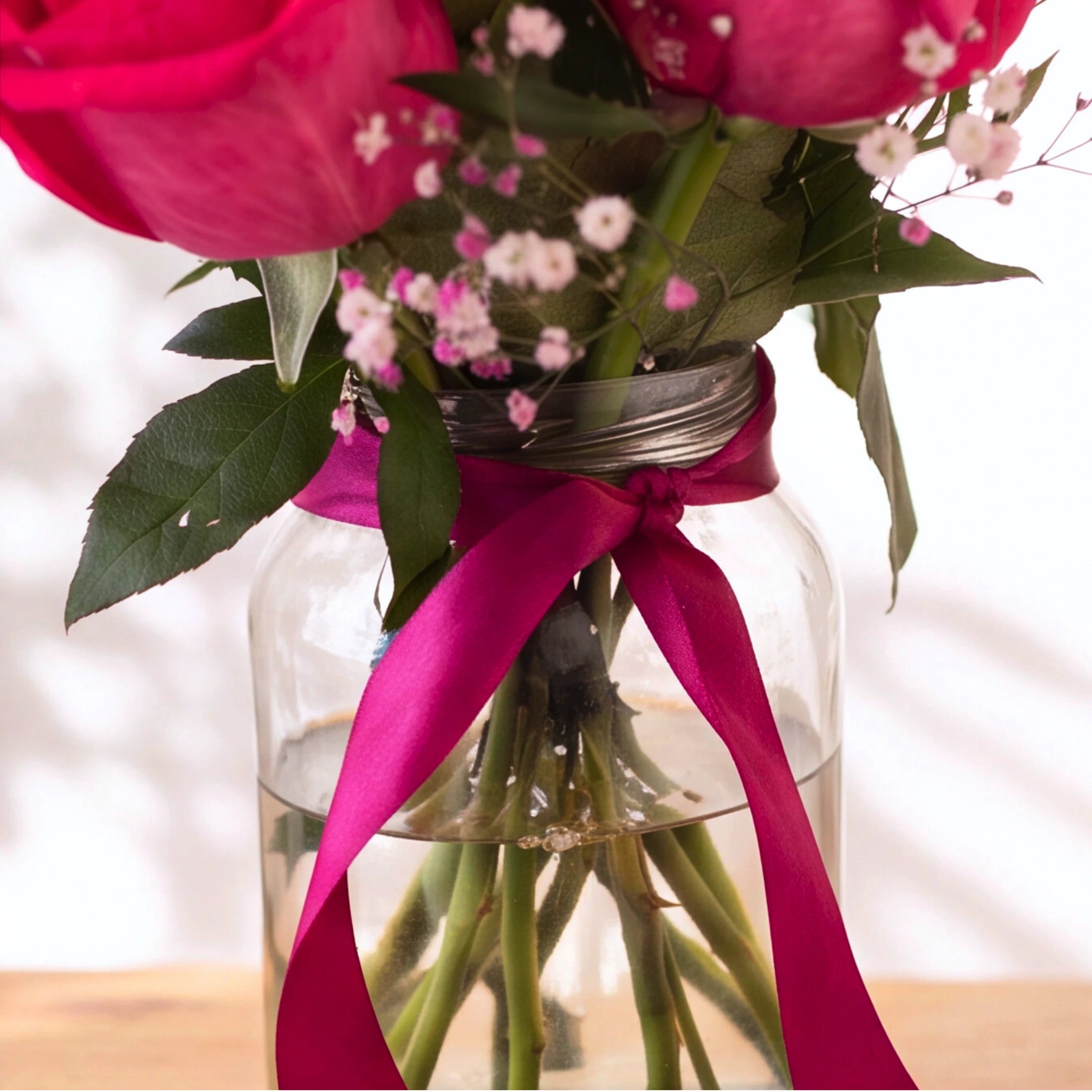 Glass flower vase finished with a deep fuchsia satin ribbon